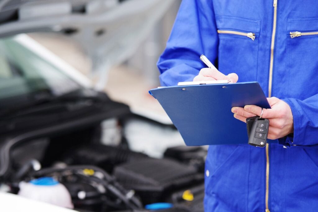 Mechaniker bei der Durchsicht eines Autos, TÜV-Untersuchung